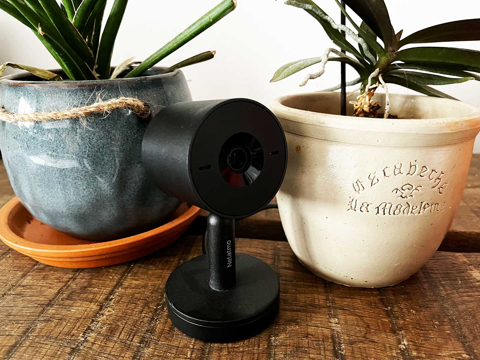Une caméra surveillance domicile sans abonnement posée sur une table à côté de plantes