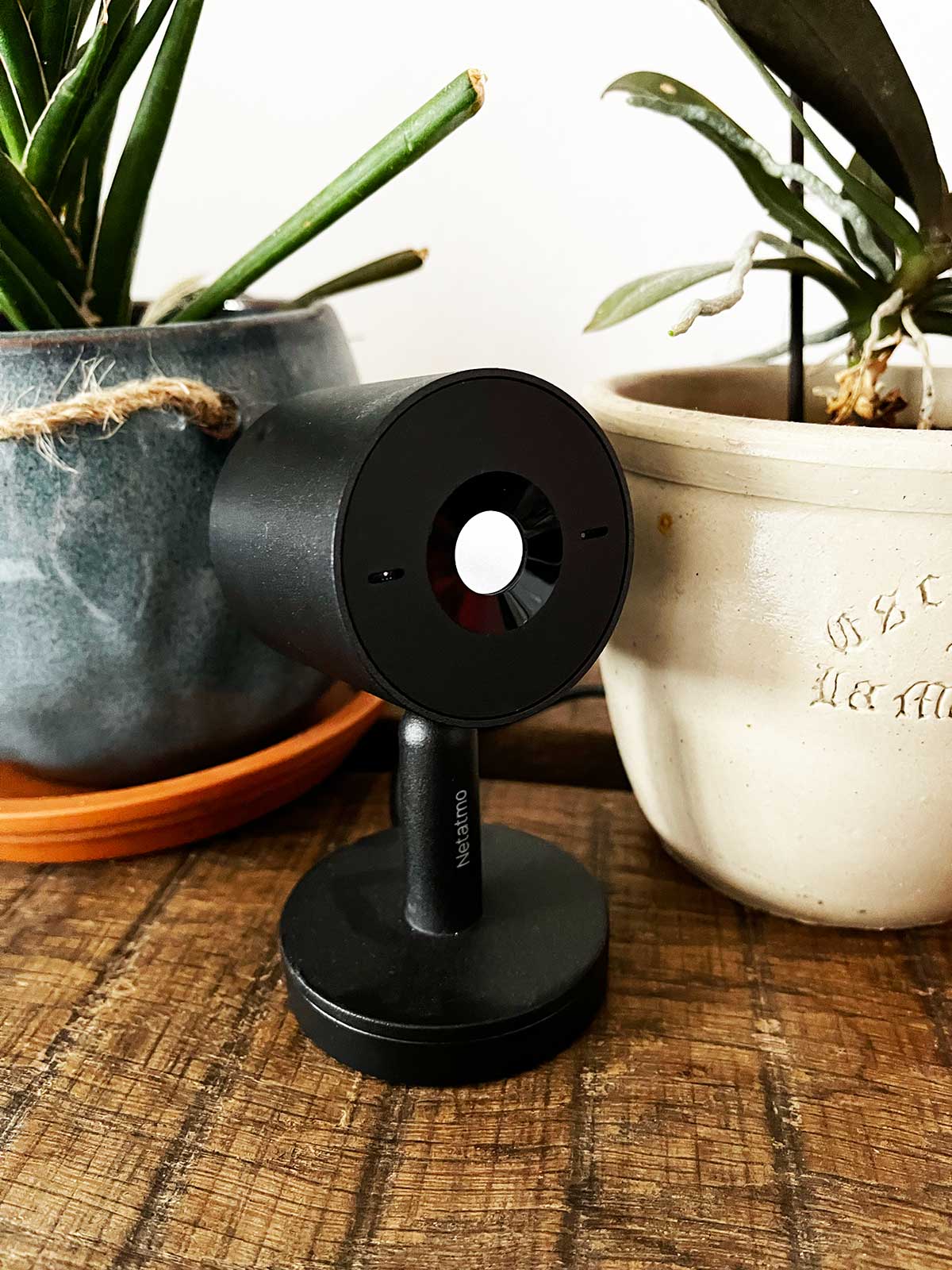 Une caméra surveillance domicile sans abonnement posée sur une table à côté de plantes